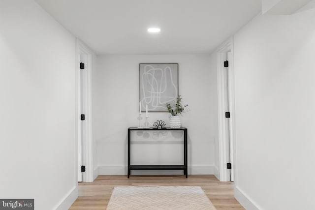 corridor with light wood finished floors, baseboards, and recessed lighting