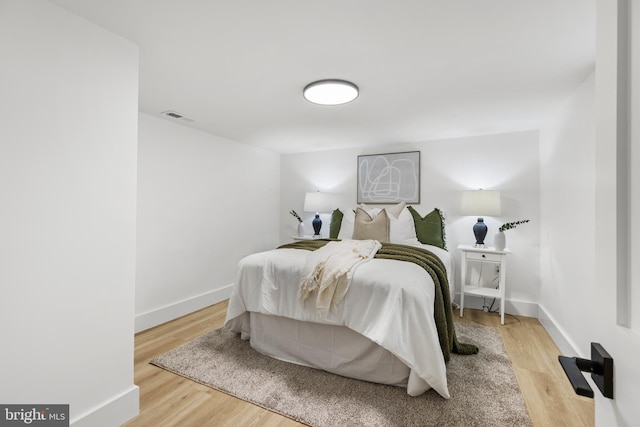 bedroom featuring wood finished floors, visible vents, and baseboards