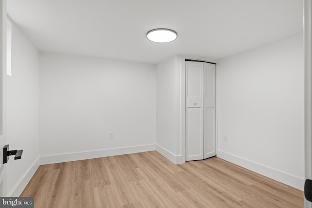 unfurnished bedroom featuring light wood-style flooring, baseboards, and a closet