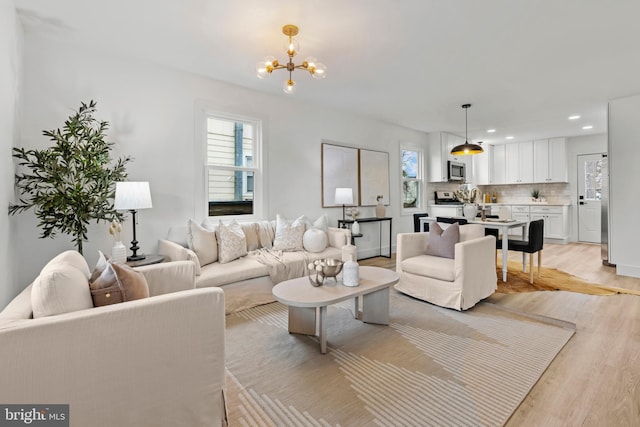 living area featuring light wood-style floors, recessed lighting, and a chandelier