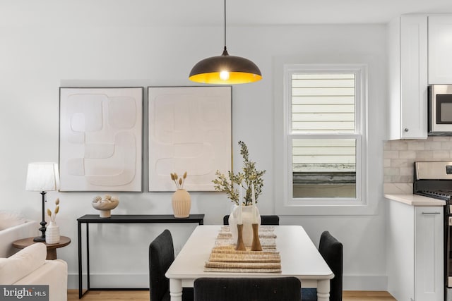 dining area with light wood finished floors and baseboards