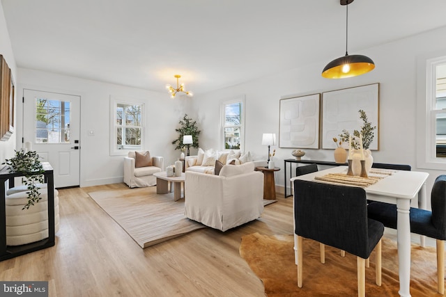 living room featuring light wood-style floors, baseboards, and a chandelier