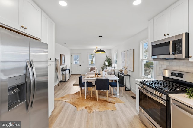 kitchen with light wood-style flooring, recessed lighting, stainless steel appliances, white cabinetry, and backsplash