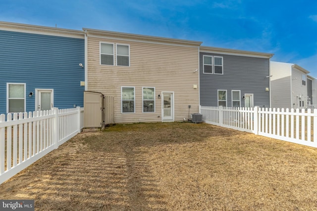 rear view of property featuring a fenced backyard, cooling unit, and a yard