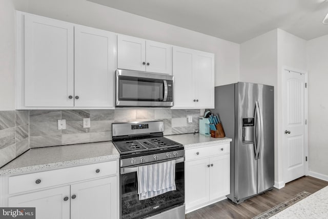 kitchen with stainless steel appliances, dark wood-style flooring, white cabinets, and decorative backsplash