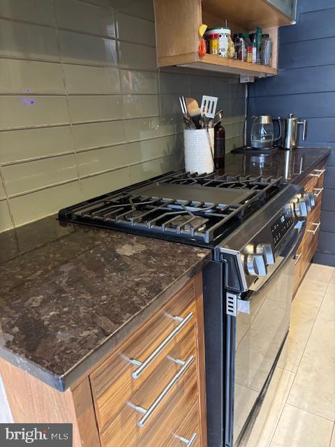 kitchen featuring gas range, tasteful backsplash, open shelves, and dark stone counters