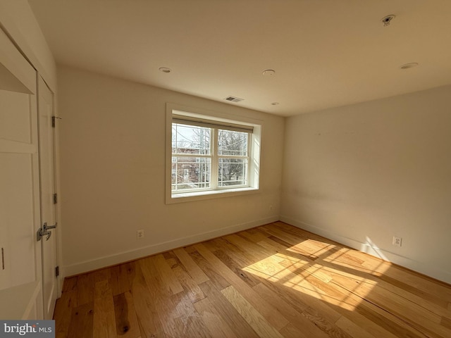 spare room with light wood-type flooring, baseboards, and visible vents