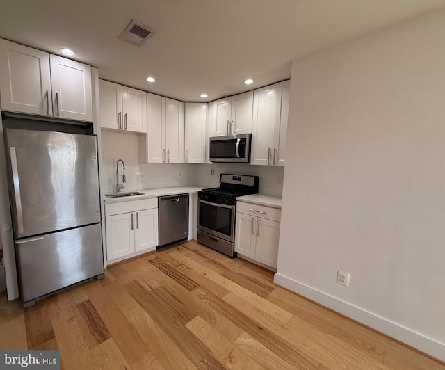 kitchen with stainless steel appliances, a sink, visible vents, white cabinets, and light countertops