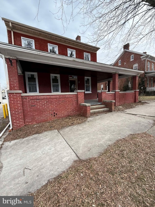 view of property with covered porch and brick siding