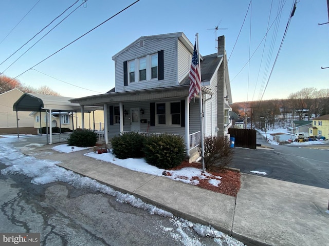 view of front of home with a chimney, a carport, and covered porch