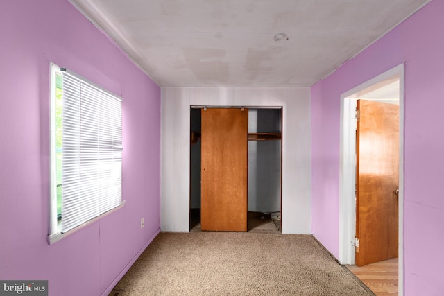 unfurnished bedroom with a closet and light colored carpet