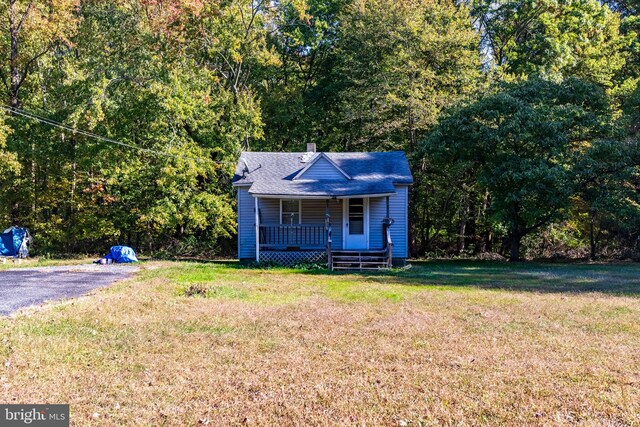 bungalow-style house with covered porch, a shingled roof, and a front yard