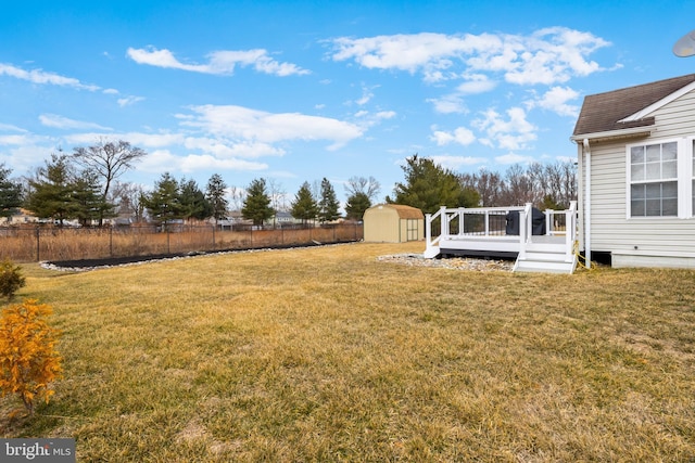 view of yard with a storage shed, a deck, an outbuilding, and a fenced backyard