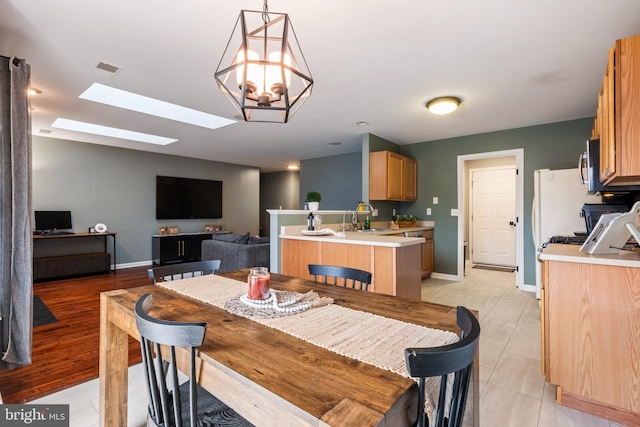 dining room featuring a skylight, baseboards, visible vents, and a chandelier