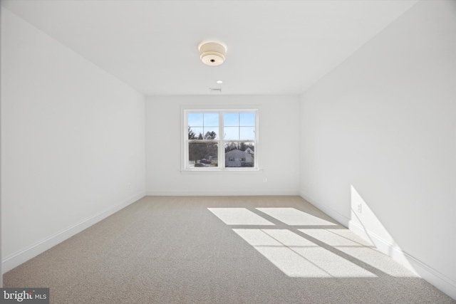 unfurnished room with light colored carpet and baseboards