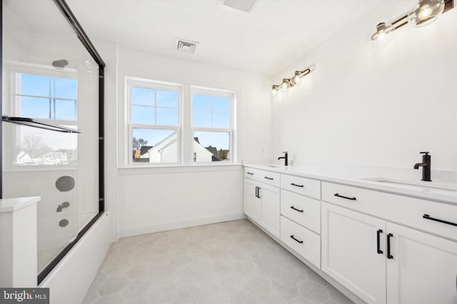 full bathroom with a sink, visible vents, combined bath / shower with glass door, baseboards, and double vanity