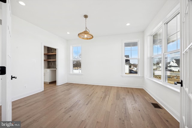 unfurnished dining area with light wood-style flooring, visible vents, and baseboards