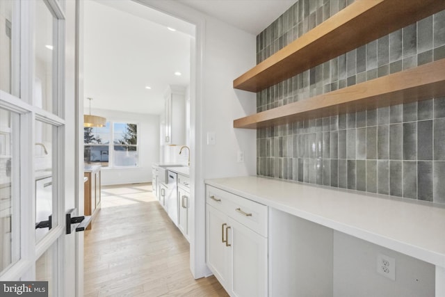 bar featuring light wood-type flooring, recessed lighting, a sink, and decorative backsplash