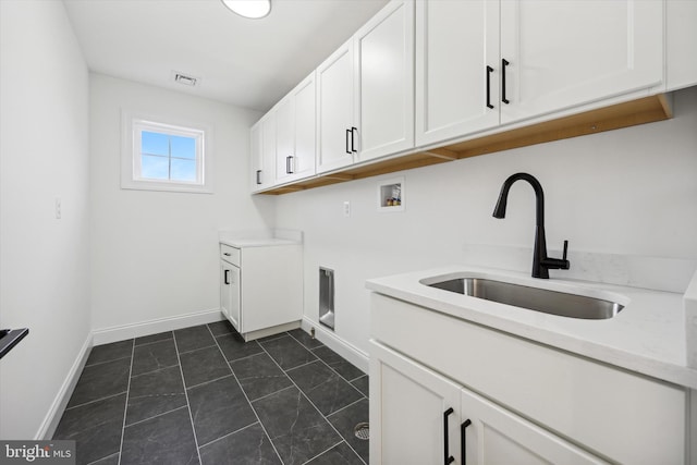 laundry room with a sink, visible vents, hookup for a washing machine, baseboards, and cabinet space