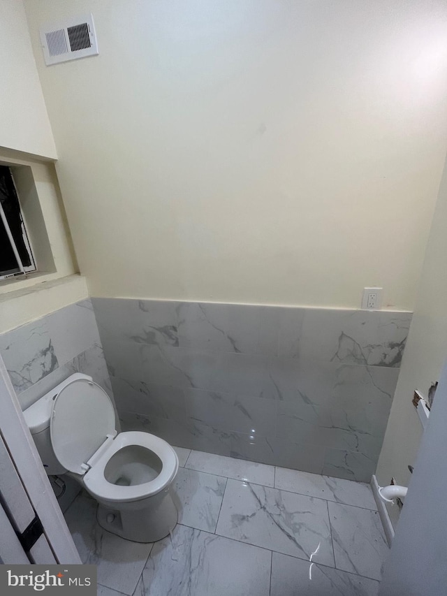 bathroom featuring tile walls and toilet