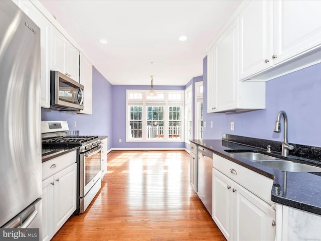 kitchen with light hardwood / wood-style flooring, hanging light fixtures, stainless steel appliances, white cabinets, and sink