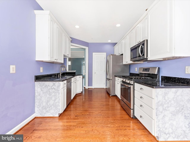 kitchen with light hardwood / wood-style flooring, sink, stainless steel appliances, and white cabinetry