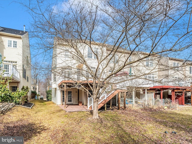 rear view of property featuring a lawn, a patio area, and a wooden deck