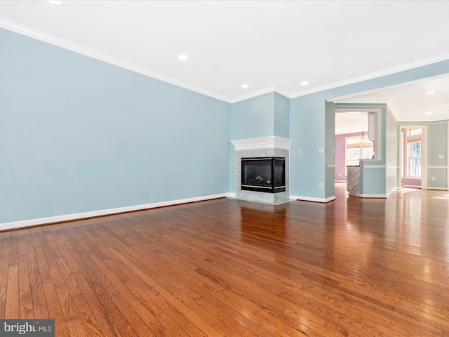 unfurnished living room with crown molding, a high end fireplace, and hardwood / wood-style floors