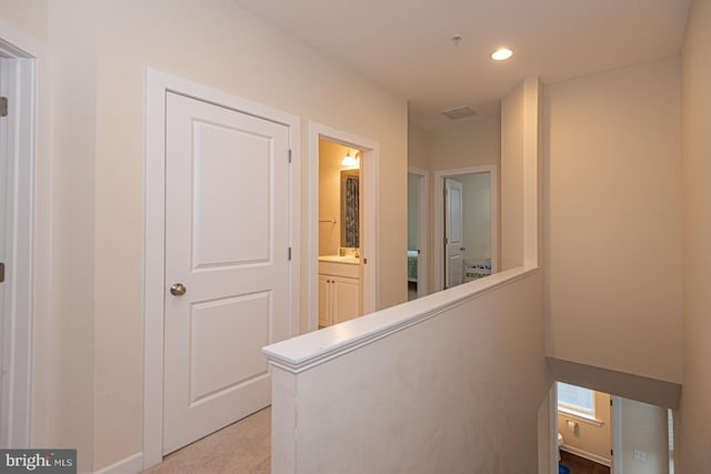 hallway with recessed lighting, light colored carpet, and an upstairs landing