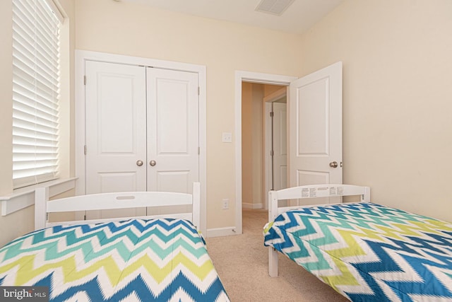 bedroom with baseboards, a closet, visible vents, and light colored carpet