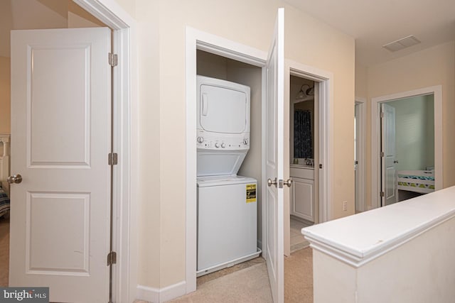 washroom featuring light carpet, laundry area, stacked washer / dryer, and visible vents