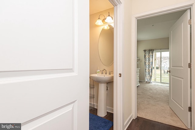 half bathroom featuring wood finished floors, a sink, and baseboards