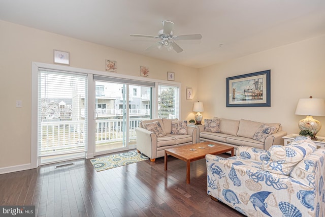 living area with dark wood-type flooring, visible vents, ceiling fan, and baseboards