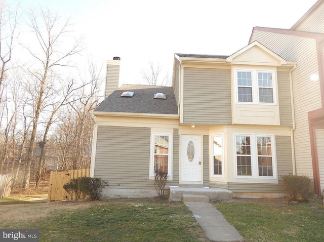 view of front of property featuring fence, a front lawn, a chimney, and roof with shingles