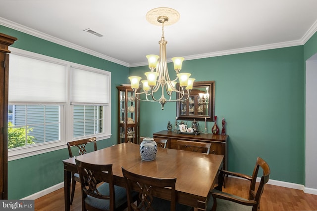 dining space with baseboards, crown molding, visible vents, and wood finished floors