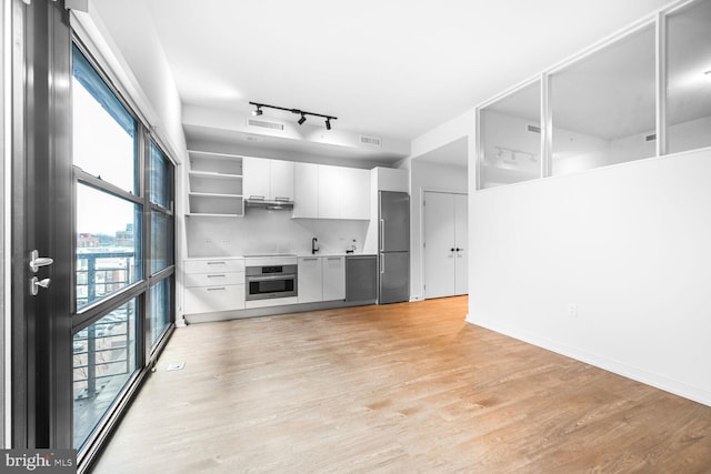 interior space with light wood-style flooring, stainless steel appliances, visible vents, white cabinets, and modern cabinets