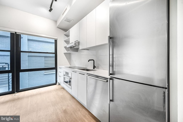 kitchen with stainless steel appliances, light countertops, visible vents, white cabinetry, and a sink