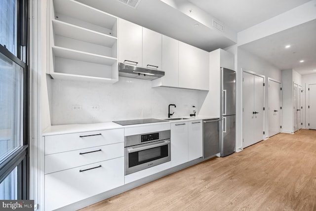 kitchen with white cabinets, under cabinet range hood, appliances with stainless steel finishes, and light countertops