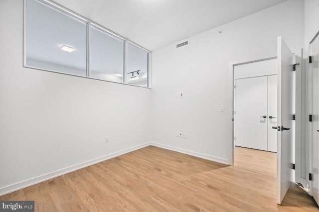 empty room featuring light wood-style flooring, visible vents, and baseboards