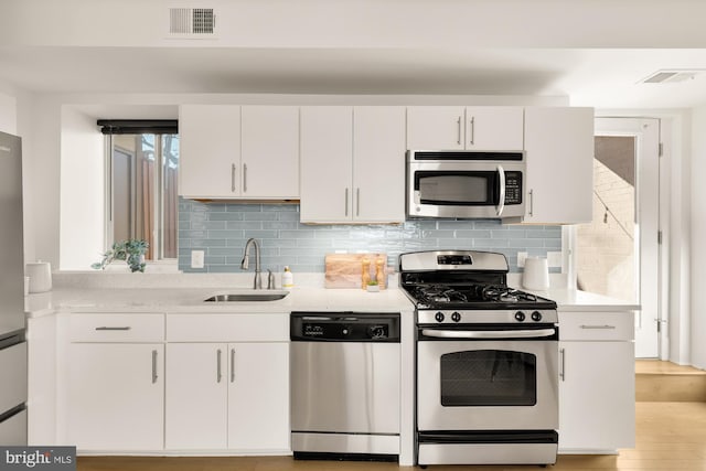 kitchen with visible vents, white cabinetry, a sink, and appliances with stainless steel finishes