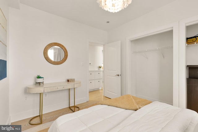 bedroom with light wood-type flooring, a closet, baseboards, and an inviting chandelier