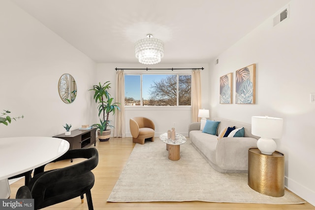 sitting room featuring a chandelier, baseboards, light wood finished floors, and visible vents