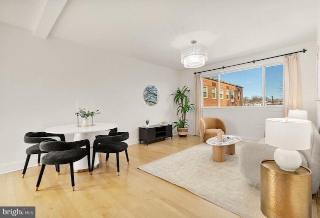 living area featuring a notable chandelier, beam ceiling, wood finished floors, and baseboards