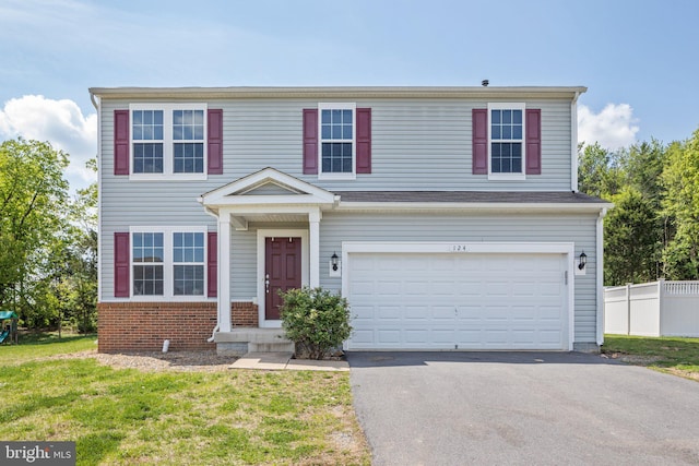 traditional-style house featuring brick siding, fence, a garage, driveway, and a front lawn