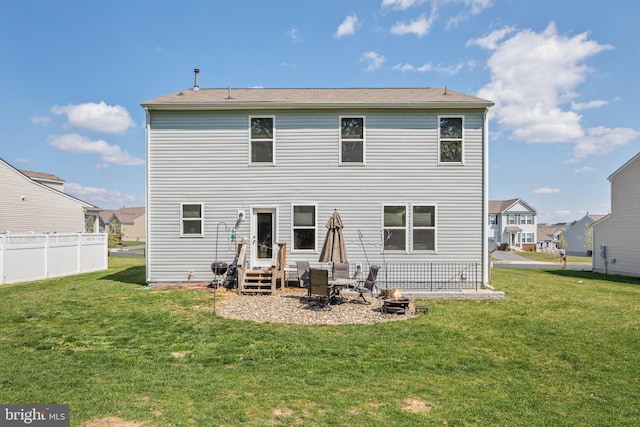 back of house featuring entry steps, a yard, fence, and a residential view