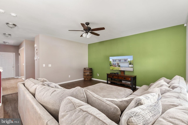 living area with a ceiling fan, dark wood finished floors, and baseboards