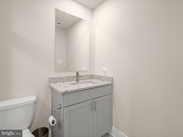 half bathroom featuring baseboards, visible vents, vanity, and toilet