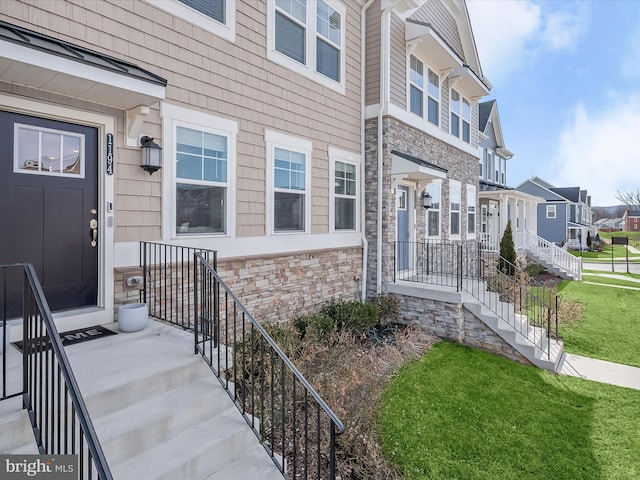 entrance to property with a residential view, stone siding, and a yard