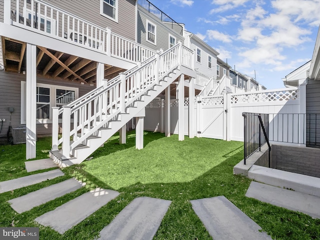 view of yard featuring a deck, a gate, stairway, and fence