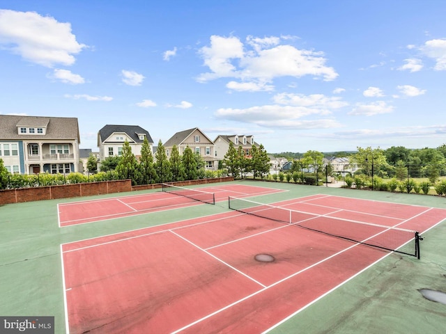 view of tennis court with a residential view and fence